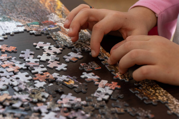 Mała dziewczynka robi puzzle w domu. Zamknij zdjęcie z selektywną ostrością. - Zdjęcie, obraz