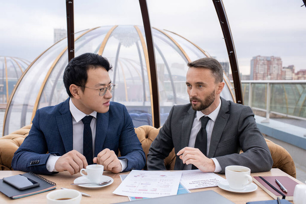 Δύο νέοι διαπολιτισμικοί επιχειρηματικοί εταίροι που εργάζονται για το τσάι και το σχεδιασμό - Φωτογραφία, εικόνα