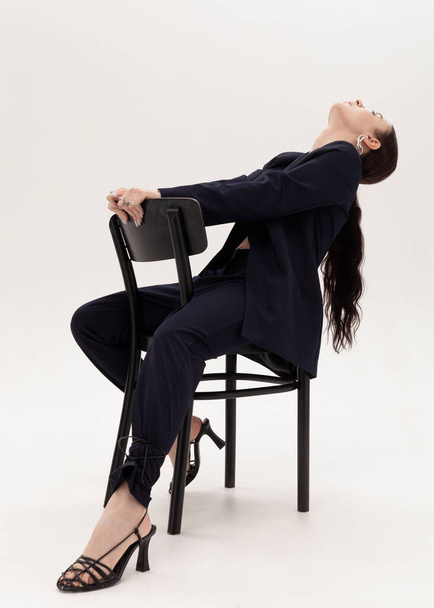 stylish cheeky girl in a pantsuit sits on a chair - Foto, immagini