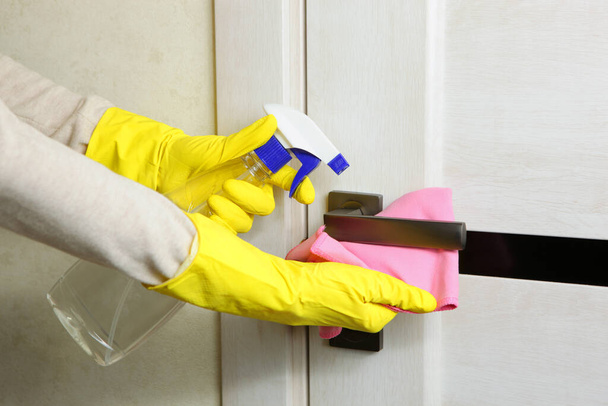 A mulher lava e desinfeta a maçaneta da porta. prevenção dos vírus disseminados. - Foto, Imagem