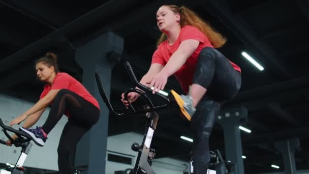 Groep atletische meisjes die aerobic rijden training oefeningen op fietsen stationaire fiets in de sportschool - Video