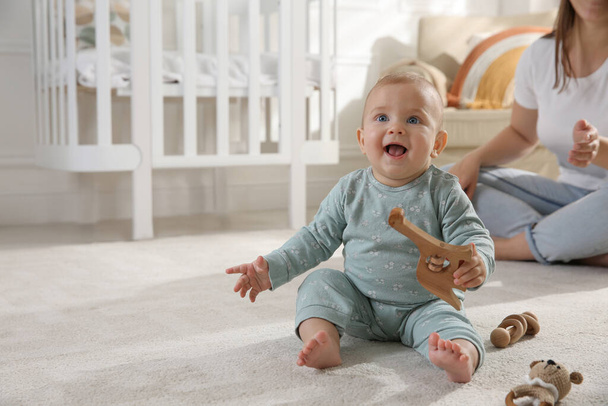 Cute baby girl playing with wooden toys and mother on floor at home - Fotografie, Obrázek