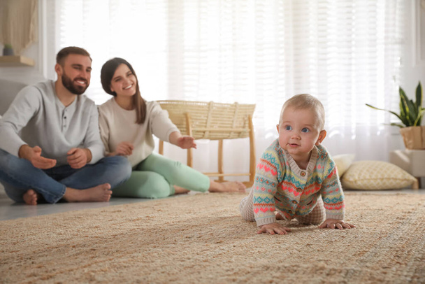 Happy parents watching their baby crawl on floor at home - Фото, зображення