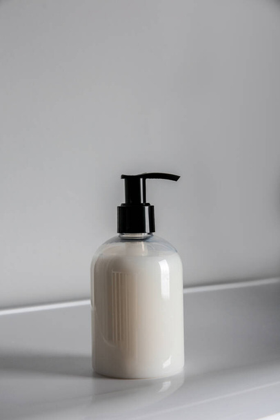 Bottle of liquid soap on table against light background - Valokuva, kuva