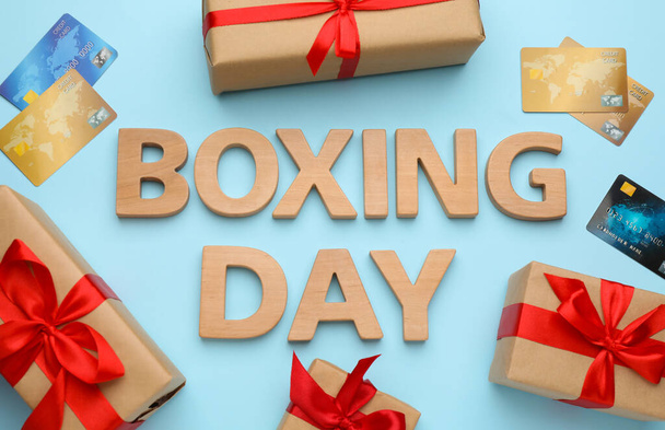 Text Boxing Day of wooden letters, credit cards and gifts on light blue background, flat lay. Sale concept - Φωτογραφία, εικόνα