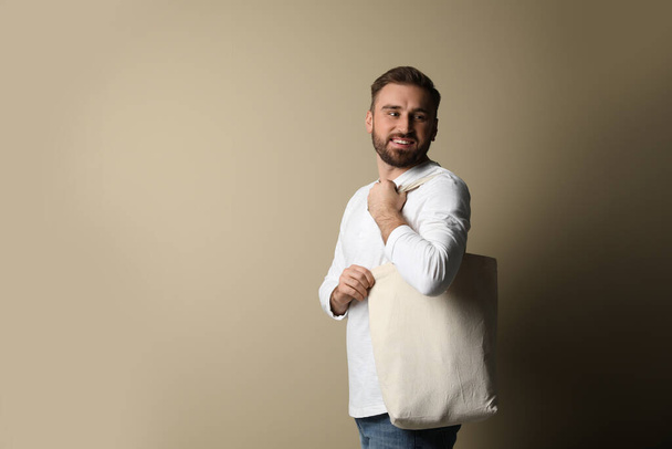 Happy young man with eco bag on beige background. Space for text - Photo, image