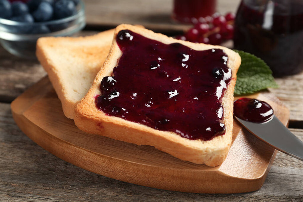 Delicious toasts with jam on wooden board, closeup - Valokuva, kuva