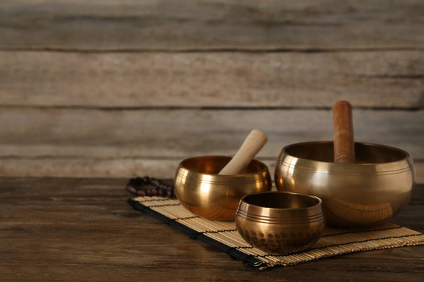 Golden singing bowls and mallets on wooden table, space for text - Fotografie, Obrázek