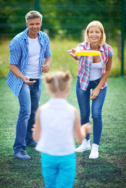 Eltern spielen Frisbee mit Tochter - Foto, Bild