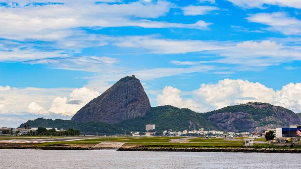 Rio de Janeiro, Brasilien - CIRCA 2021: Foto vom Zuckerhut, Pao de Acucar, mit Landebahn des Flughafens Santos Dumont und Guanabara-Bucht tagsüber - Foto, Bild