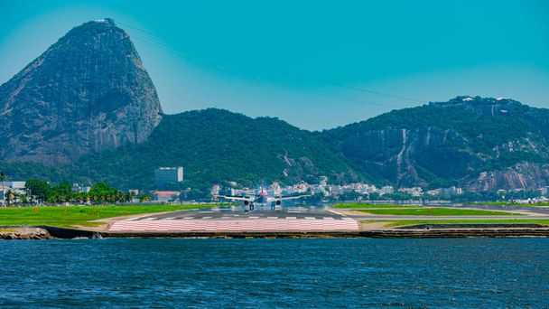 Rio de Janeiro, Brésil - CIRCA 2020 : Avion commercial atterrissant sur la piste de l'aéroport national Santos Dumont. Il est possible de voir la baie de Guanabara et la montagne du pain de sucre, attractions touristiques de Rio - Photo, image