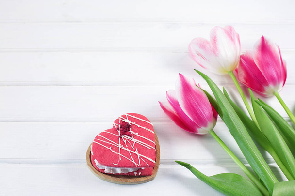 Barevné tulipány a srdce cookie na bílém dřevěném pozadí. - Fotografie, Obrázek