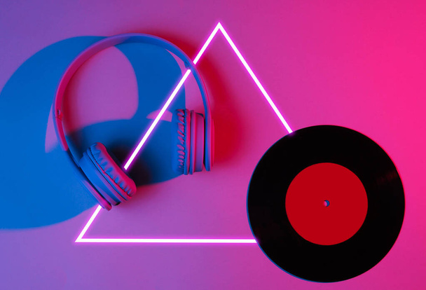 Headphones with vinyl record. 80's synth wave and retrowave glowing triangle futuristic aesthetics. Old fashioned abstraction concept - Photo, Image