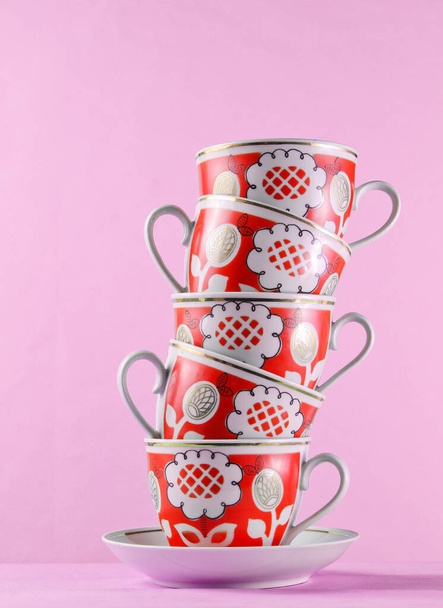 Montón de tazas de cerámica antiguas en la mesa de madera contra la pared rosa - Foto, Imagen