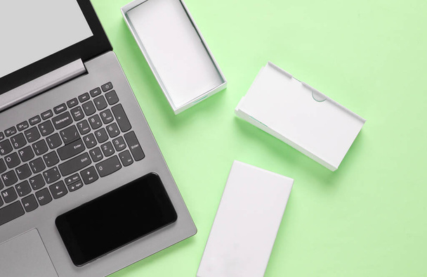O conceito de unboxing, techno blogging. Caixa com novo smartphone, laptop em fundo verde pastel. Vista superior - Foto, Imagem