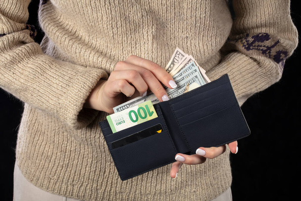 Naisten käsissä, ruskea lompakko euroilla ja dollareilla. - Valokuva, kuva