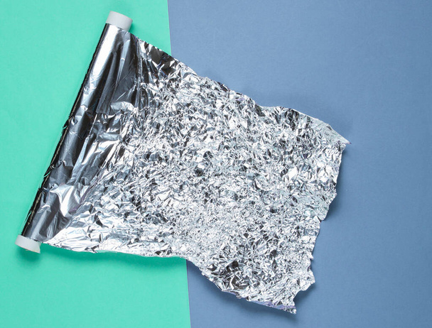 A roll of crumpled foil on colored background. Top view - Foto, afbeelding