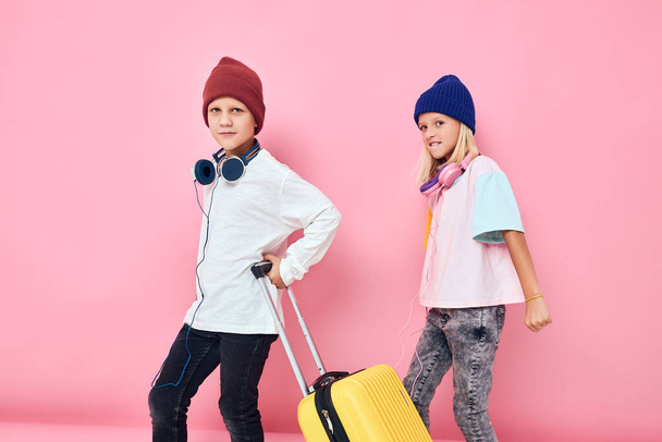 Portrait of a girl and a boy with a yellow suitcase in his hands Childhood lifestyle concept - Foto, Bild