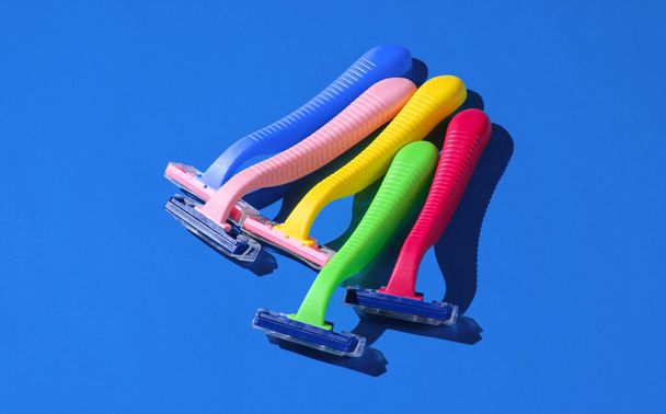Beleza e moda conceito de arte pop. Muitas lâminas de barbear de plástico coloridas em fundo azul. Minimalismo
 - Foto, Imagem
