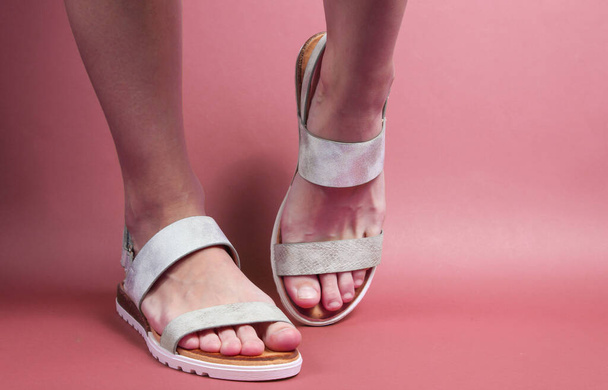 Female legs in trendy leather sandals on pink background. Summer footwear. Your stylish loook - Foto, Imagem