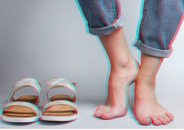 female bare feet in jeans and sandals on a white background. Studio fashion shot. Glitch effect. Crop photo - Foto, Imagem