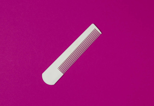 White plastic comb on pink background. Hair care, beauty concept. Top view - Fotoğraf, Görsel