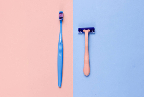 Cuidado personal minimalista, concepto de belleza. Navaja de afeitar de plástico, cepillo de dientes sobre un fondo azul-rosa pastel. Vista superior
 - Foto, imagen