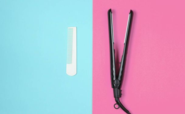 Minimalistic beauty and fashion still life. Comb and hair straightener on blue pink background. Top view, flat lay - Foto, Bild