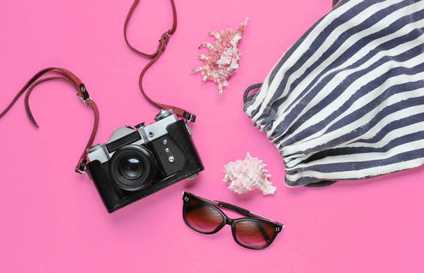 Matkailutarvikkeet, retro kamera vaaleanpunaisella taustalla. Matka rannalle, loma. Kesän minimalistinen tausta. Tasainen lay matkailu allegoria - Valokuva, kuva