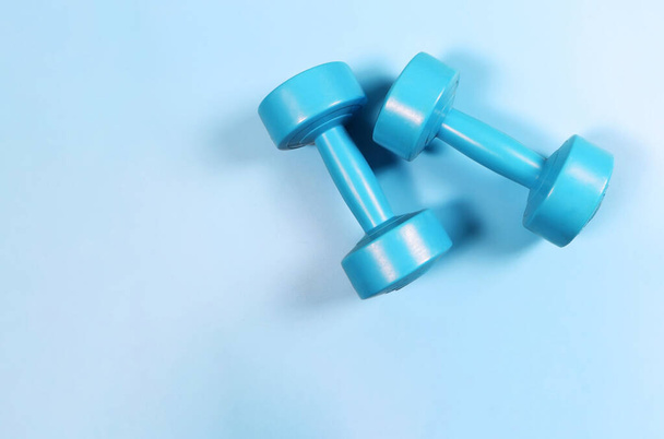 Top view or flat lay of blue dumbbells on blue background with copy space. Sports and healthy lifestyle concept. - Photo, Image