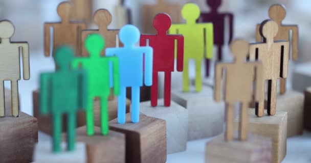Multicolored figures of people in middle of wooden figures of crowd. - Footage, Video