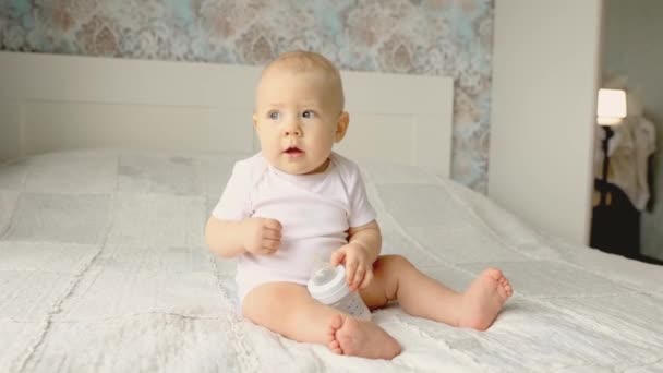 baby jongen zit glimlachend op het bed in de slaapkamer - Video
