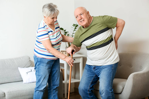 Senior woman helping her husband with back pain at home - Photo, image
