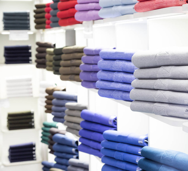 Polo t-shirt magasin intérieur. Magasinez des étagères avec des chemises en coton coloré. - Photo, image