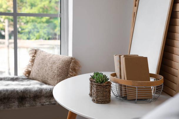 Кавовий столик з рамкою, книжками та вазонами біля дерев'яного розкладного екрану у вітальні
 - Фото, зображення