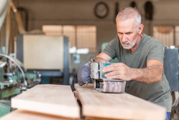 Мужчина, сосредоточенный на работе с ручной шлифовкой - Фото, изображение