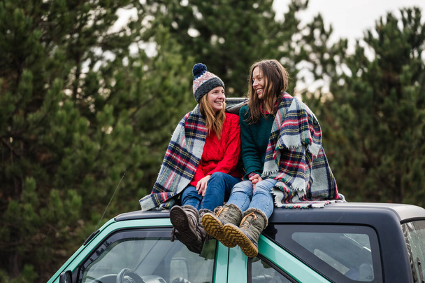 Chicas sentadas en la parte superior del coche y disfrutar de la naturaleza de invierno - Foto, imagen