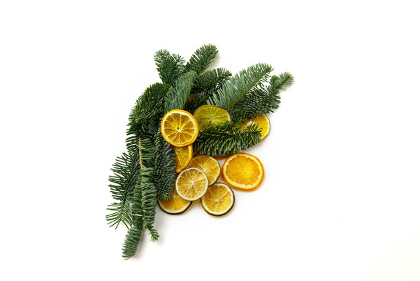 Fir branches and a bunch of dried citrus slices on a white background. Winter concept - Photo, Image