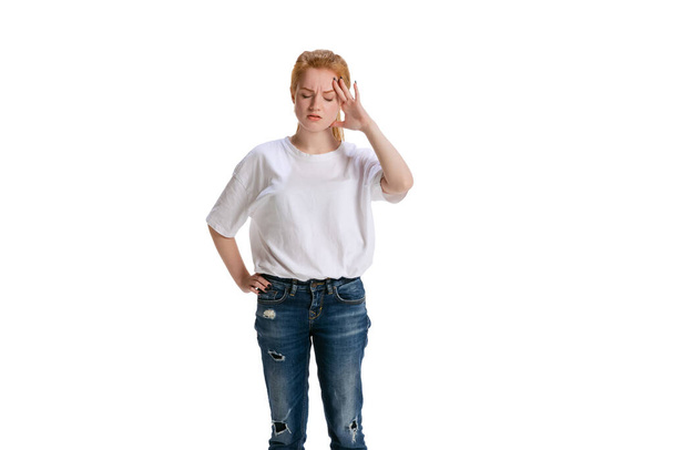 Обрезанный портрет молодой девушки касающейся головы в раздражении изолированы на белом фоне - Фото, изображение