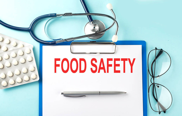 Paper with text FOOD SAFETY on blue background with stethoscope and pills - Фото, изображение