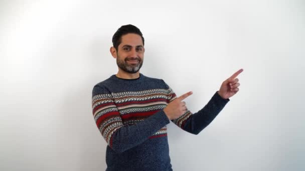 Portrait of happy caucasian man pointing with two hands and fingers to the side. Glad person showing things at indoor studio shot isolated on white background - Footage, Video