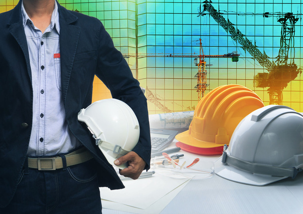 Инженер, стоящий с белым защитным шлемом против строителя
 - Фото, изображение
