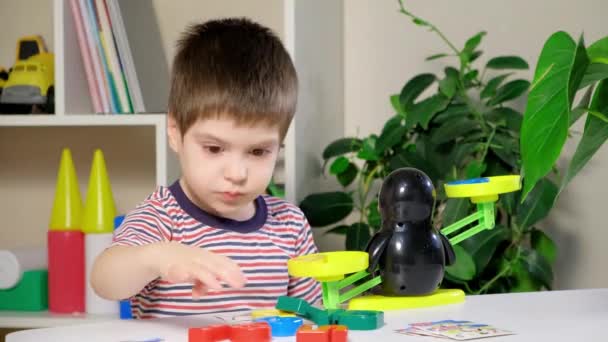 Un niño preescolar aprende números, pesa números en una balanza de pingüinos - Metraje, vídeo