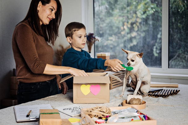 Charity Care Pet box, donation box, gift package for pet shelter. Happy family, mother, kid and dog putting staff into donation box for homeless pets. Care Package Delivery, - Foto, Imagem