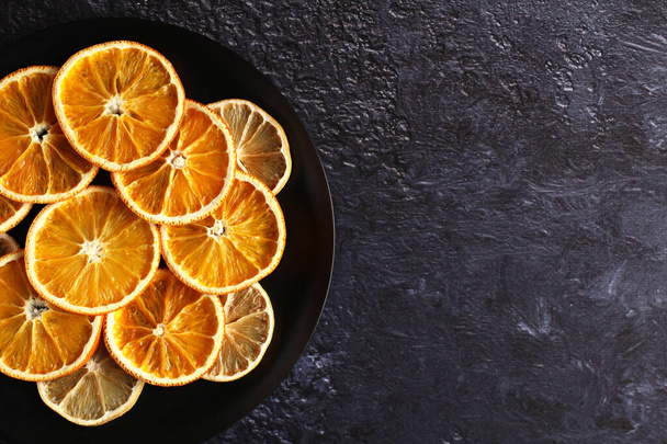 dried slices of orange and lemon fruit on a plate on a dark background with a copy space - Photo, Image