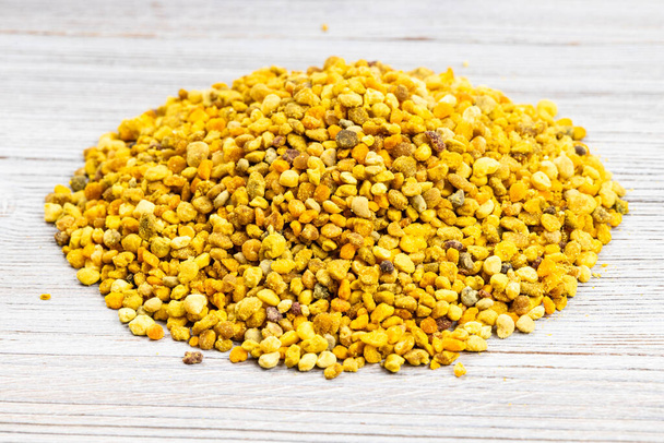 pile of natural bee pollen close up on gray wooden board - Foto, immagini
