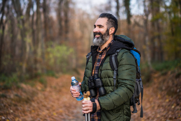 Image of man holding bottle  of water while hiking. - Foto, Bild