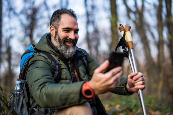 Image of hiker using phone while spending time in nature. - Foto, Imagem