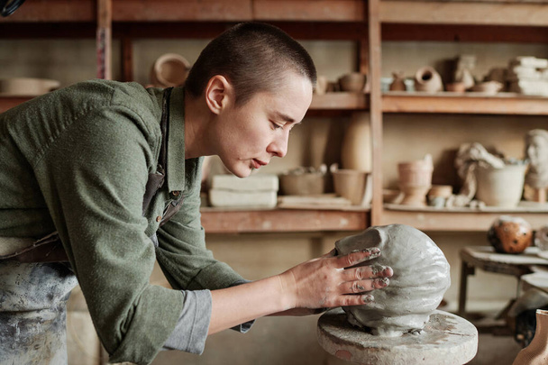 Жінка робить людське обличчя з глини
 - Фото, зображення