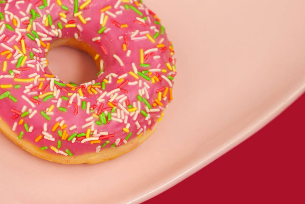 Donut with pink icing and colorful Sprinkles in plate, selective focus. Top View. - Foto, Imagem